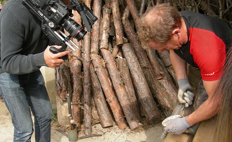 A man is filming a black smith at work